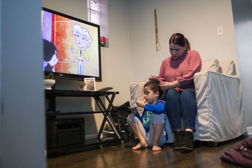 Vannessa Olivera plays with son Liam’s hair as they watch TV at their home in Kilbourn Park.