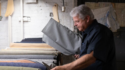 Jay Greenfield searches through rolls of fabric to bring a sample to a customer at Martin Greenfield Clothiers in Brooklyn, New York, on August 11, 2026.
