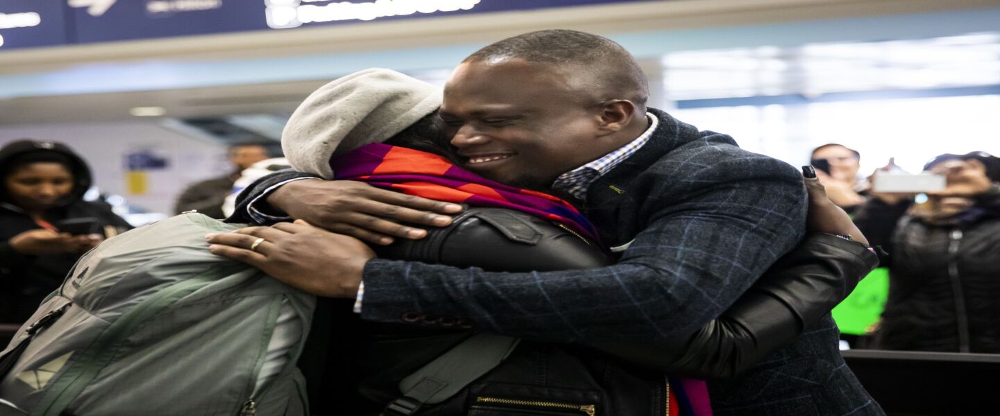 Celestine Mugisha and his wife, Winniefred Akello, embrace at O’Hare International Airport as they are reunited after living apart for more than three years, Jan. 22, 2020. Mugisha and Akello were married in Uganda in September 2016 and, days later, Mugisha moved to Chicago as part of the United States’ refugee resettlement program. More than three years later, Akello was also resettled through the program.