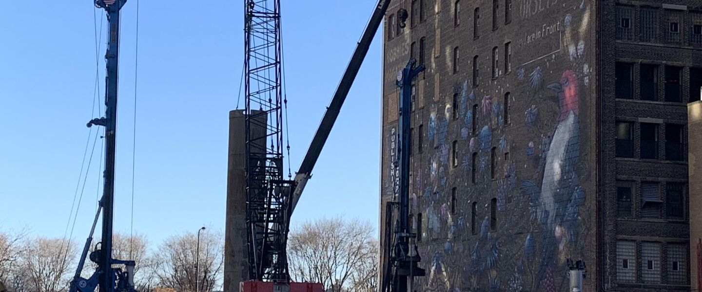 Construction crews working at the site of a new condo tower that will rise next to the eight-story office building on which the bird mural faces north.