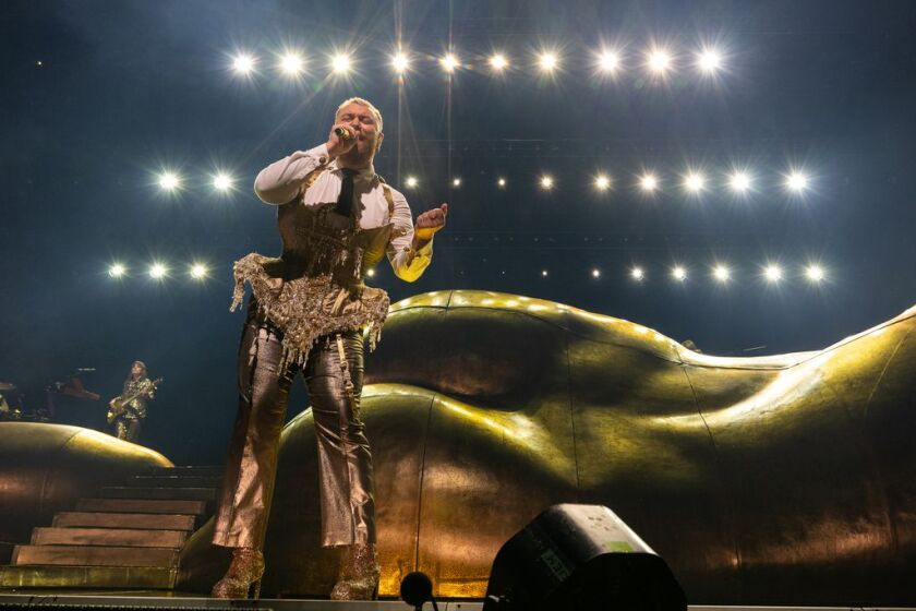 A reclined, golden statue of Aphrodite provides the backdrop for Sam Smith during their concert at the United Center.