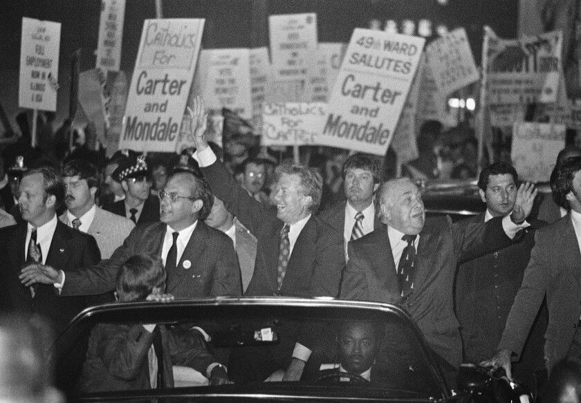 Democratic presidential nominee Jimmy Carter (center) with Chicago Mayor Richard J. Daley (right) and Sen. Adlai Stevenson III, D-Ill. (left), wave from an open-top limousine during a torchlight parade in Chicago on Sept. 9, 1976. The parade was a traditional hallmark of presidential campaigns.