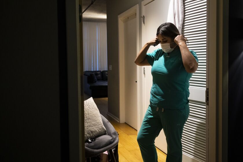 Nurse practitioner Capri Reese removes her face mask, sanitizes her shoes and put her scrubs in the washing machine before immediately showering at her South Loop apartment after a 12-hour shift at Roseland Community Hospital, where three patients suffering from COVID-19 died, Tuesday afternoon, April 28, 2020.