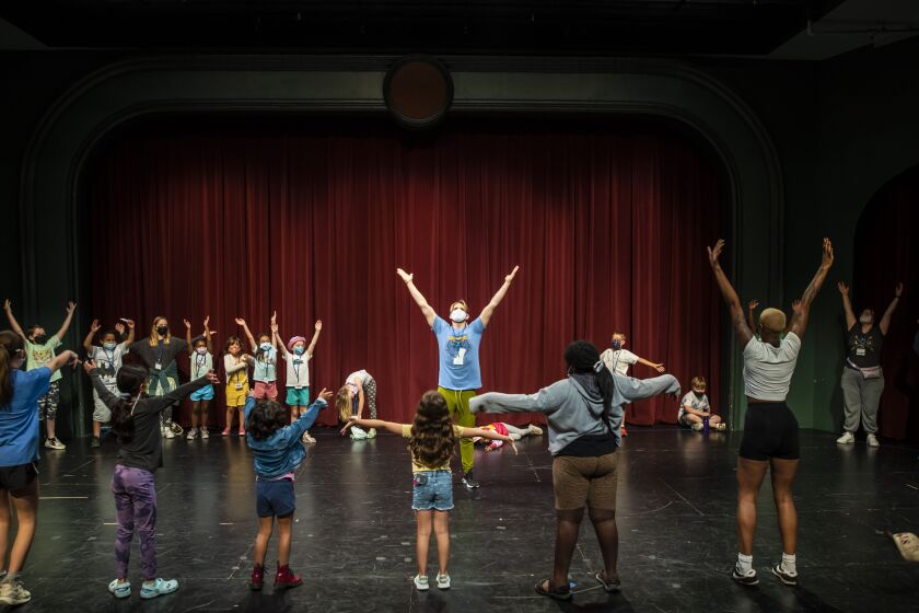 Chazie Bly (centre) warms up children early in the day on July 11 at Hearts to Art, a summer camp for children whose parents have passed away.