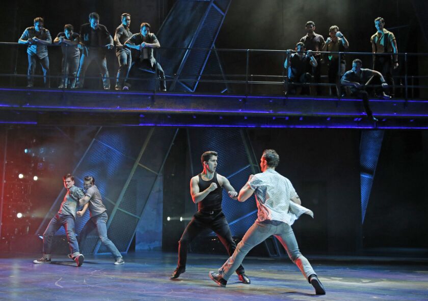 Bernardo (Adrian Aguilar, left foreground) takes a swing at Riff (Jeff Smith) in the Paramount Theatre production of ‘”West Side Story.” (Photo: Liz Lauren)