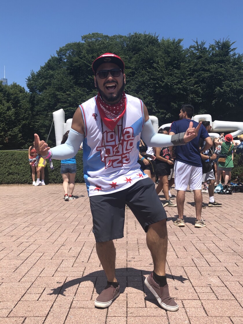 Brian Meza sports a Lollapalooza shirt in front of the Lollapalooza sign.