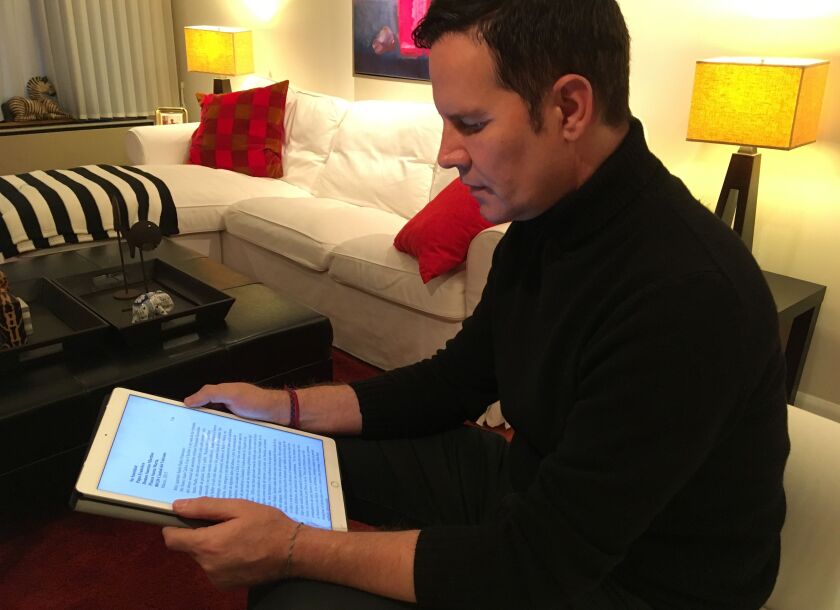 Juan Carlos Cruz reads from his tablet during an interview with The Associated Press in Philadelphia, on Sunday. | AP photo