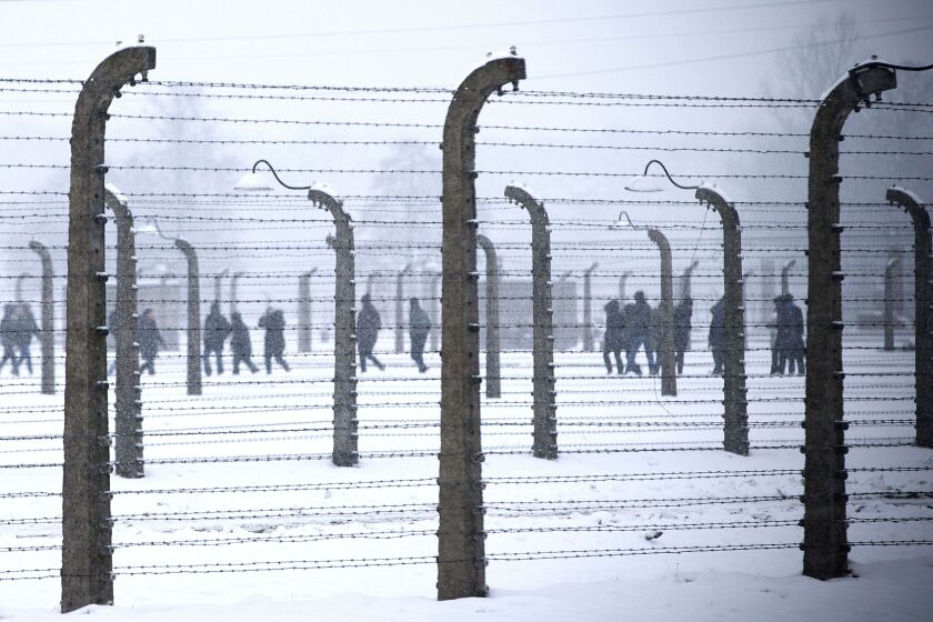 Visitors are seen walking behind barbed-wire fences at the memorial site of the former Nazi concentration camp Auschwitz-Birkenau in Oswiecim, Poland on January 25, 2015, days before the 70th anniversary of the liberation of the camp by Russian forces. JO