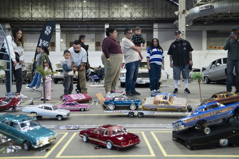 Alec Mendoza (in blue hoodie), 4, plays with a remote controlled lowrider with the help of his dad Alex Mendoza (in white shirt and brown pants) during "Slow and Low" at Navy Pier, Saturday, Oct. 11, 2025.