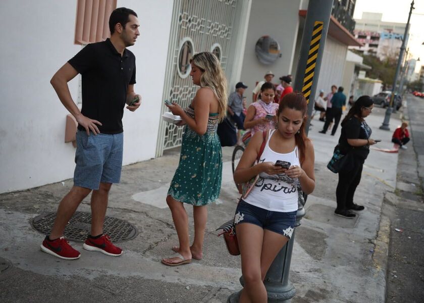 People take advantage of the Optico Fiber companies free Wi-Fi zone setup for those that don’t have cell service to connect with friends or loved ones as they wait for the damaged telephone grid to be fixed after Hurricane Maria passed through the area on