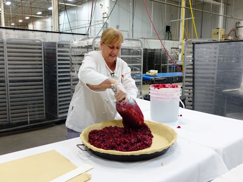 Eli’s Cheesecake executive pastry chef Laurel Boger adds the 50 pounds of fresh cherry filling to the “big pie” that will top this year’s “Big Cake” at Taste of Chicago. | Maureen Schulman