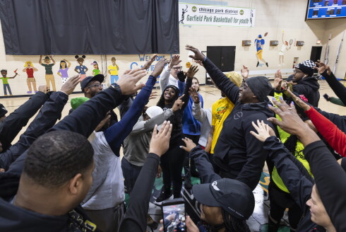 Jackie Hoffman, founder of the Peace Runners, at the center of a huddle before a weekly walking/running gathering at the Garfield Park Fieldhouse on Chicago's West Side.