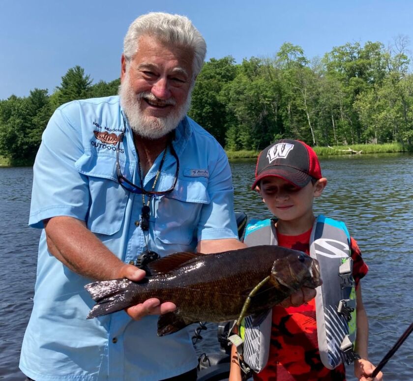 Guide Mike Mladenik holds a smallmouth bass for a young client. Provided photo