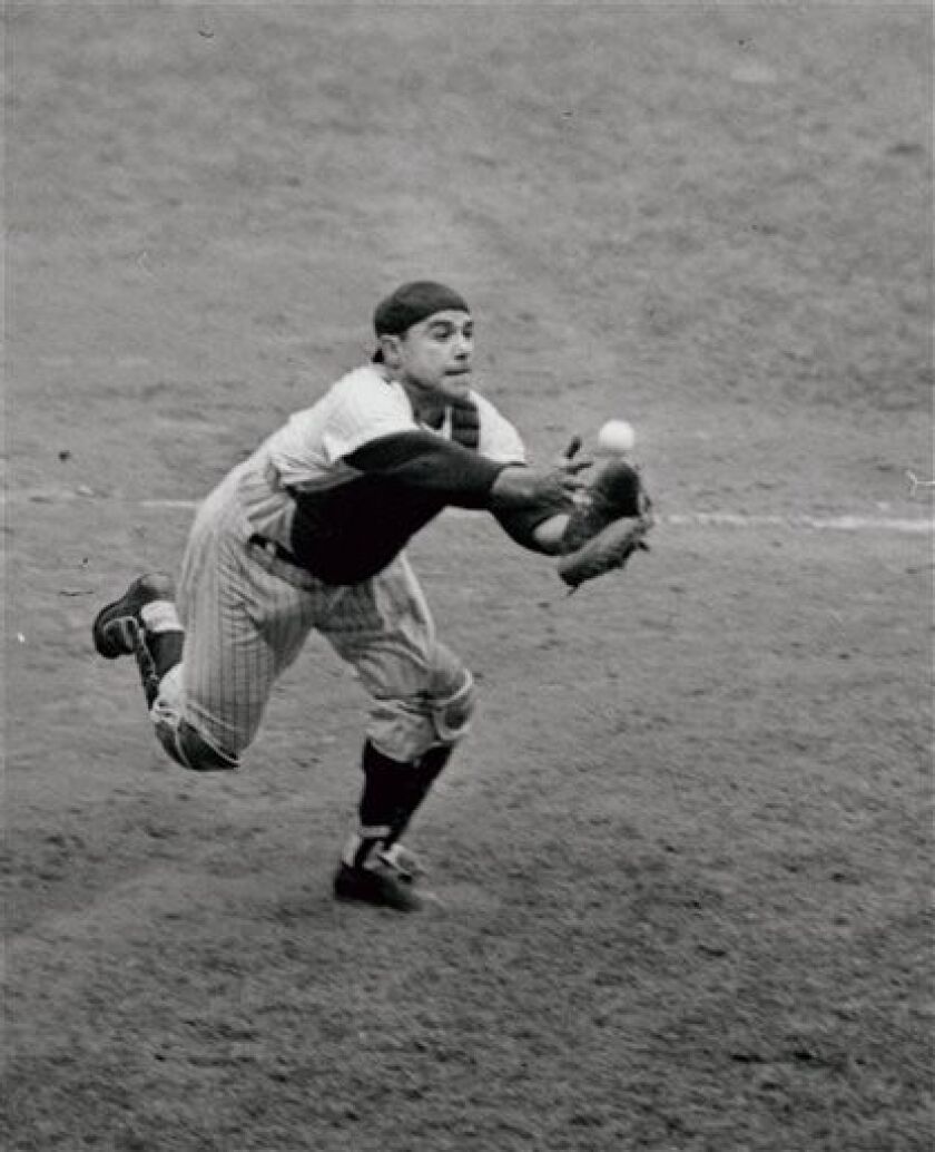 Catcher Yogi Berra of the New York Yankees grabs for a foul pop bunted by pitcher Tony Pena of the Kansas City Athletics in the eighth inning of the game at New York’s Yankee Stadium on Sept. 2, 1962. | AP file photo