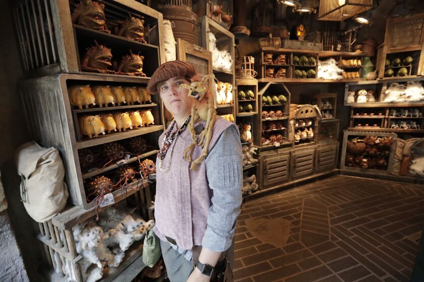 A shop keeper displays creatures that will sit on your shoulder and other merchandise for sale during a preview of the Star Wars themed land, Galaxy’s Edge in Hollywood Studios at Disney World.