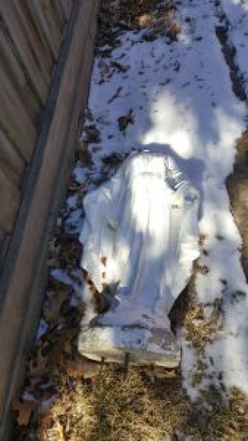 A vandalized statue of the Virgin Mary lies in the back yard of a home at 97th and Menard where it had stood nearly 30 years. A priest is asking for the culprits to return the stolen head. (Photo supplied)
