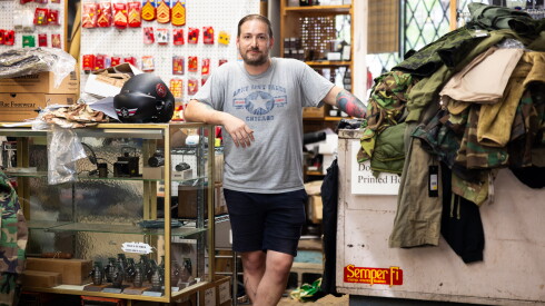 Army Navy Sales owner Adam Hirsch stands at the counter of his Lake View military surplus store.