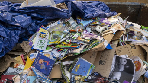 A Dumpster filled with storybooks sits outside an elementary school.