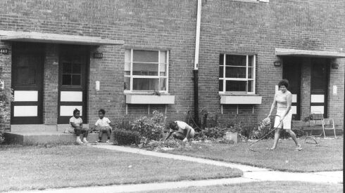 A 1975 image of LeClaire Courts residents tending a garden and watering the front lawn.