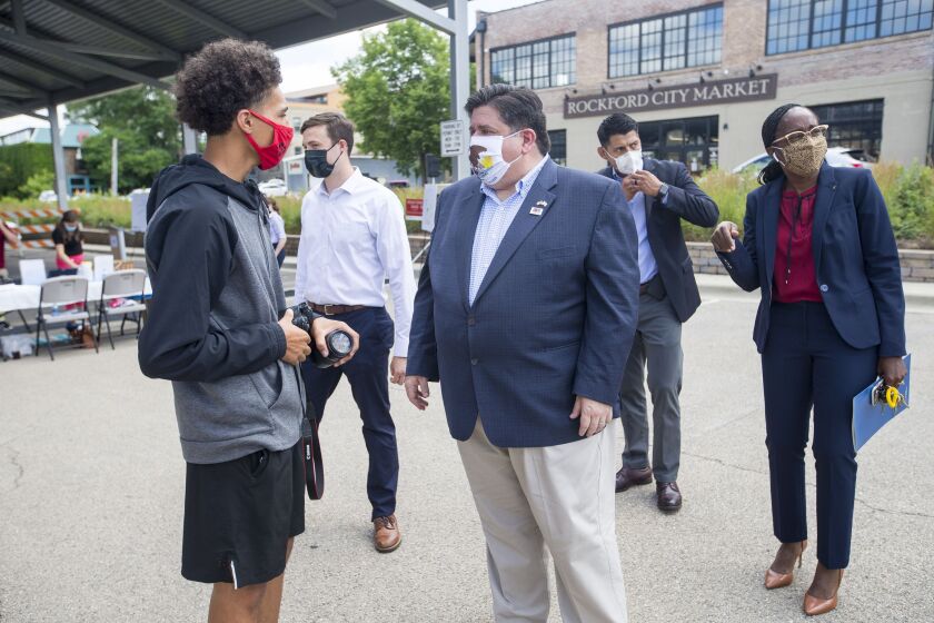 Gov. J.B. Pritzker, right, greets videographer Tamir Bell, left, at City Market in Rockford last week.