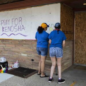 Members of the community paint over the boarded up windows of businesses near 57th Street and 7th Avenue as the city of Kenosha prepares fo the fourth day of civil unrest after police shot Jacob Blake, Wednesday evening, Aug. 26, 2020.