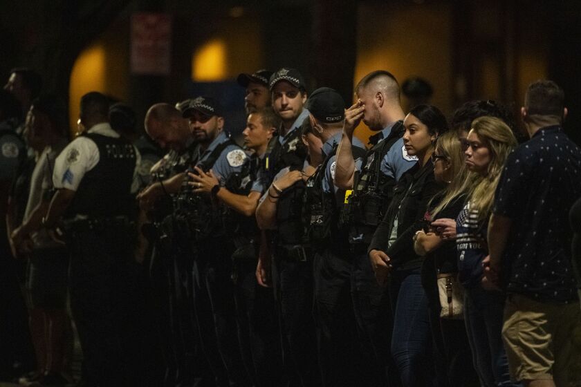 A Chicago police officer rubs his eyes while standing in line with other officers outside the Cook County Medical Examiner’s Office right before a procession for a Chicago police officer who was shot and killed earlier during a traffic stop at 63rd and Bell, Sunday, Aug. 8, 2021.