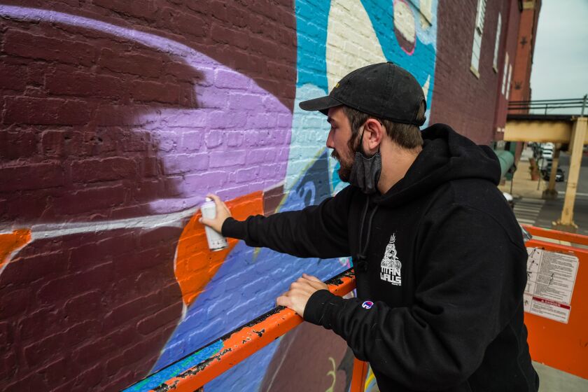Blake Jones, one of the artists who worked on the new West Loop mural, fills in more of the outline for his towering purple rabbit.