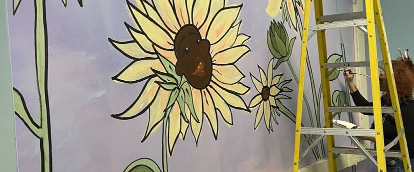 A mural in Martin Luther King Jr. College Preparatory High School in North Kenwood features several sunflowers, including one with a person’s face in the center of it.