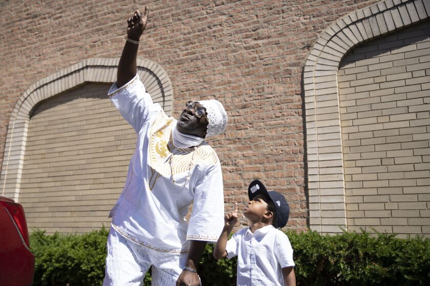 Olumide Olupitan and his grand-nephew Tacari Zarell Wright Jr. point to the sky outside Sacred Memories Funeral Home in South Shore on Sept. 5. Olupitan says he now feels a sense of responsibility to help Tacari find the right path as he grows older now that his brother isn’t around.