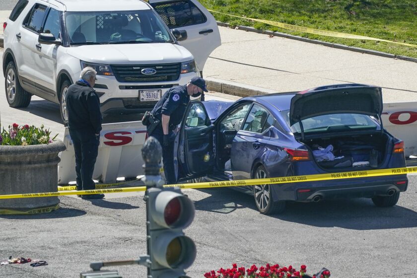 U.S. Capitol Police officers stand near a car that crashed into a barrier on Capitol Hill in Washington, Friday, April 2, 2021.