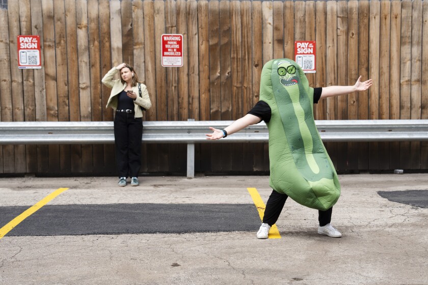 A mascot wearing a pickle costume entertains people in line outside The Cubby Bear during Pickle Fest in Wrigleyville on May 3.