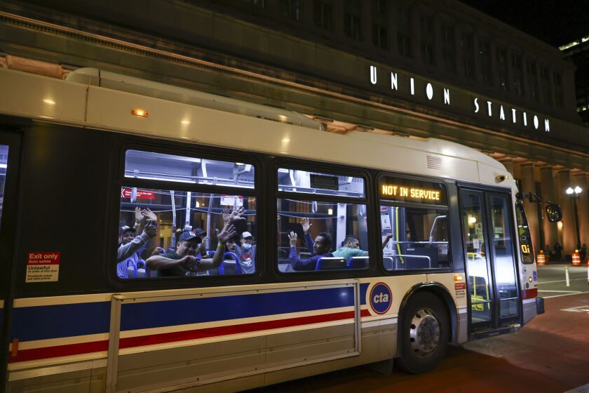 Migrants wave outside Union Station as a bus leaves to take them to a refugee center Wednesday night, Aug. 31, 2022. Migrants from Venezuela were transported from Texas and dropped off at Union Station.