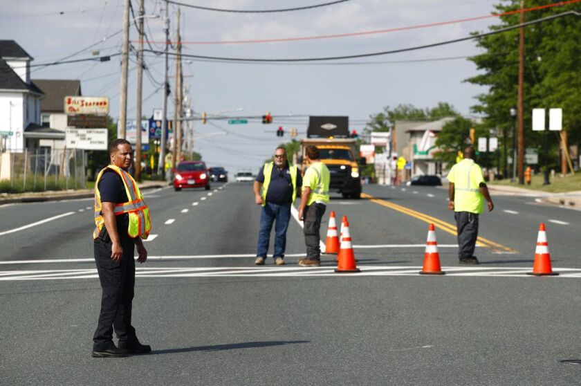 Officials guard a roadblock near a scene where a Baltimore County police officer died, while investigating a suspicious vehicle, Monday, May 21, 2018, in Perry Hall, Md. Heavily armed police swarmed into the leafy suburb, searching for at least one armed