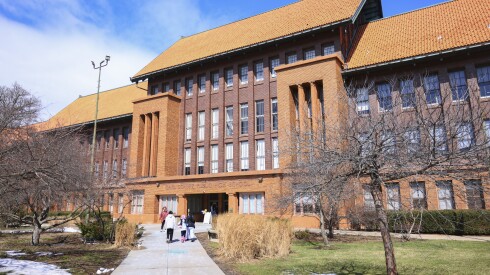 A large brick high school with grass on the front lawn.