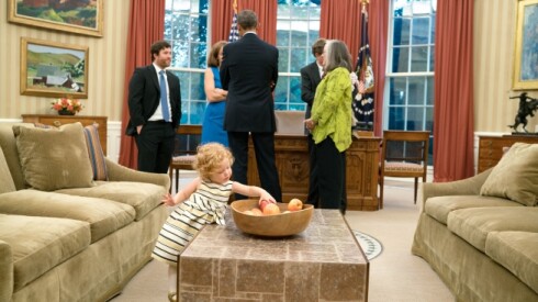 Lillian McNally, de veintiún meses, toma una manzana mientras el entonces presidente Barack Obama se reúne con su madre, Amanda Anderson, y a su padre, Matthew McNally, en la Oficina Oval el 8 de octubre de 2015.
