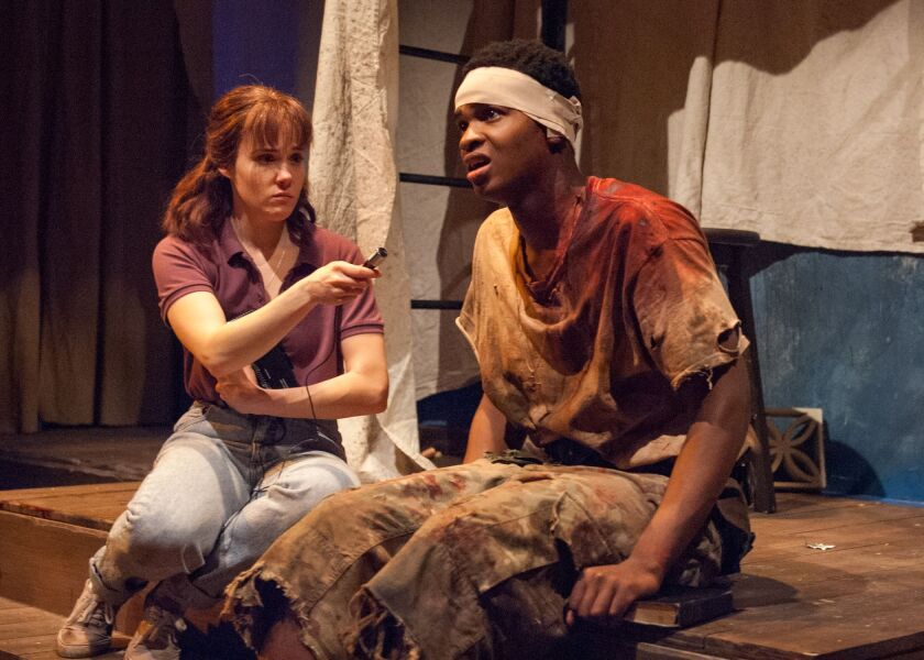 Chris (Kearstyn Keller, left), attempts to comfort child soldier Pika (Freedom Martin) by having him tell her his sins in TimeLine Theatre’s production of “Cardboard Piano.” | Lara Goetsch