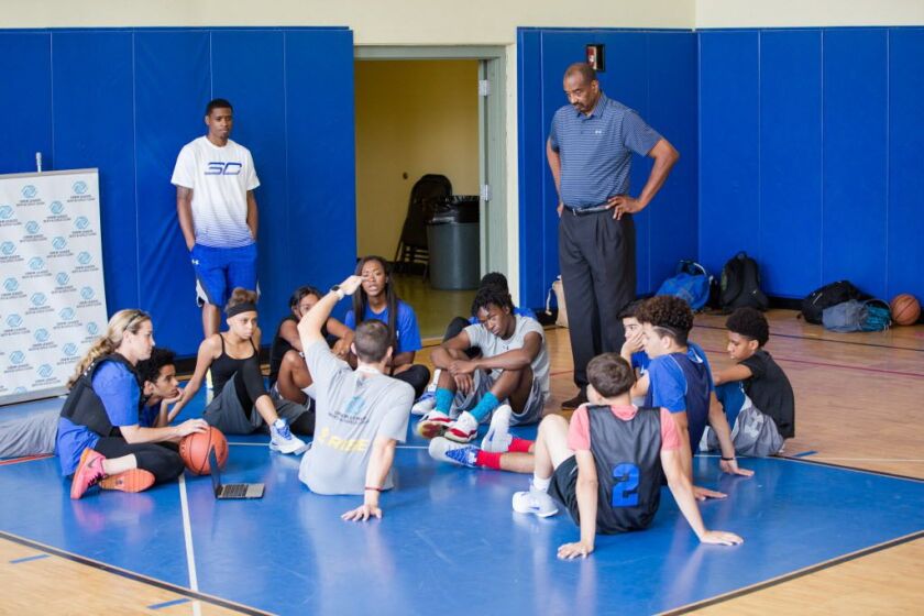 Former NBA player Wallace “Mickey” Johnson (standing at right) talks to kids in the “Building Bridges Through Basketball” program. He talked about growing up in North Lawndale, and about how an officer in his community helped him stay on the straight and