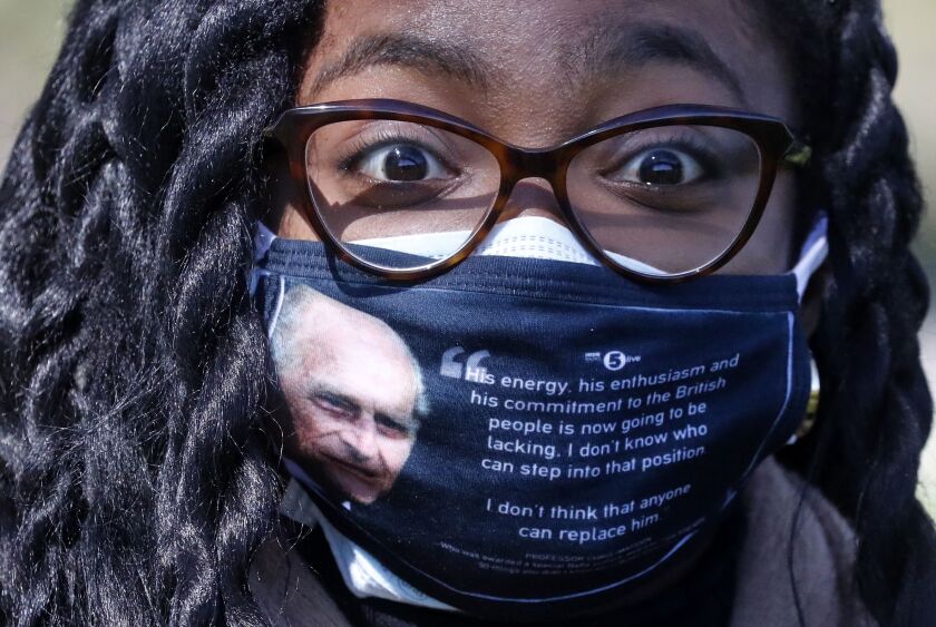 A woman wears a face covering with a picture of the Duke of Edinburgh as he walks along the Long Walk in Windsor on Saturday.