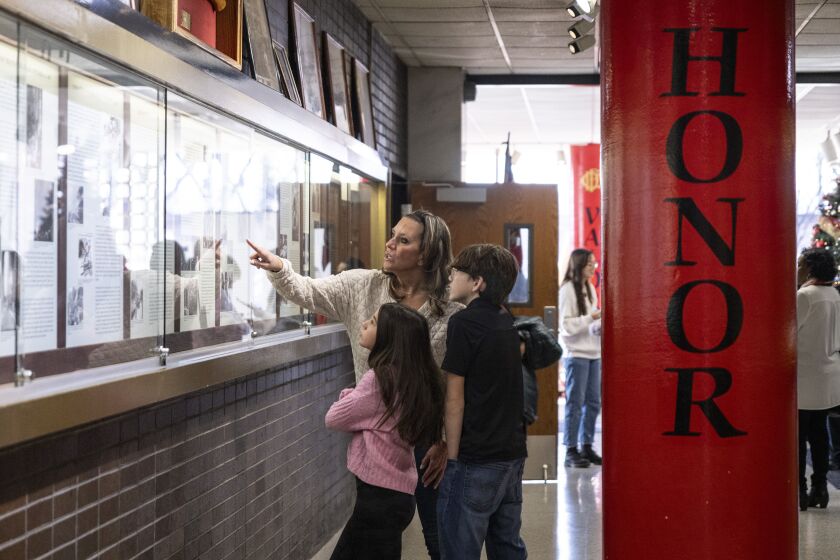 Jennifer Mayoski, wife of fallen Chicago Fire Department firefighter Jason Mayoski, and their two children, 13-year-old Jason and 12-year-old Brooke, look at the commemorative wall of CFD history after a news conference at the Quinn Fire Academy about the EMWQ Retirees’ Widows’ and Children’s Assistance Fund, Monday, Dec. 11, 2023.