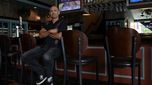 Restaurateur Robert Gomez sits in a chair at the bar of one of his restaurants