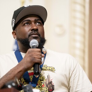Darrin Laye, head coach of the boys' basketball team at John Marshall Metropolitan High School, addresses the crowd during a celebration for the team's state title. The event was held in the auditorium of the high school, 3250 W. Adams St. in East Garfield Park on Thursday, April 2, 2026. The team won the won the Illinois High School Association Class 1A state championship in March.