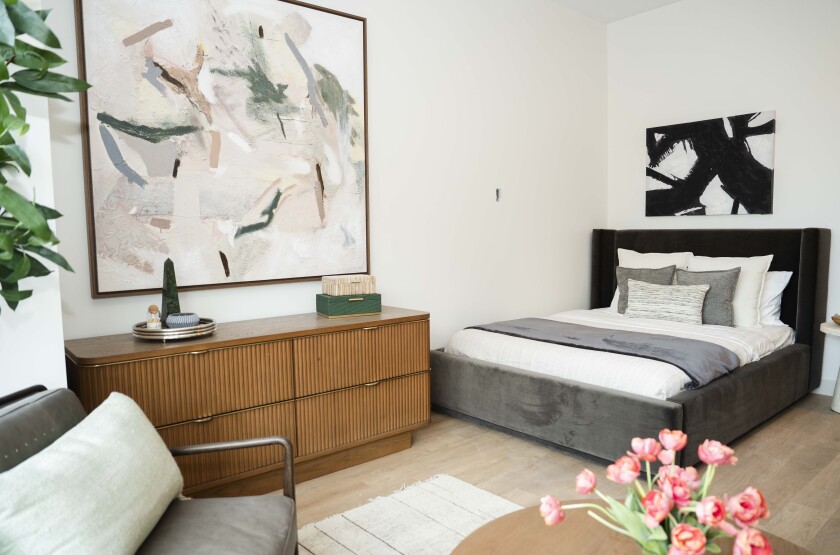 Partial view of a studio unit with a bed, dresser and seating