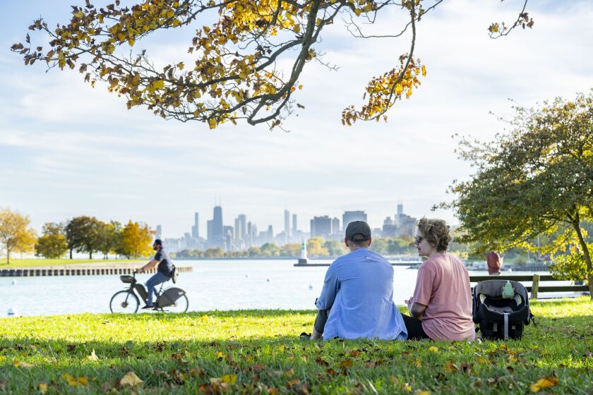 A couple sits in the grass near Montrose Harbor as temperatures neared 80 degrees, Tuesday, Oct. 24, 2023.