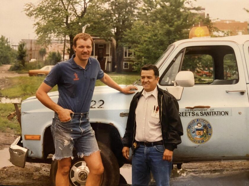 Raúl Montes, right, stands in front of his Department of Streets and Sanitation truck.