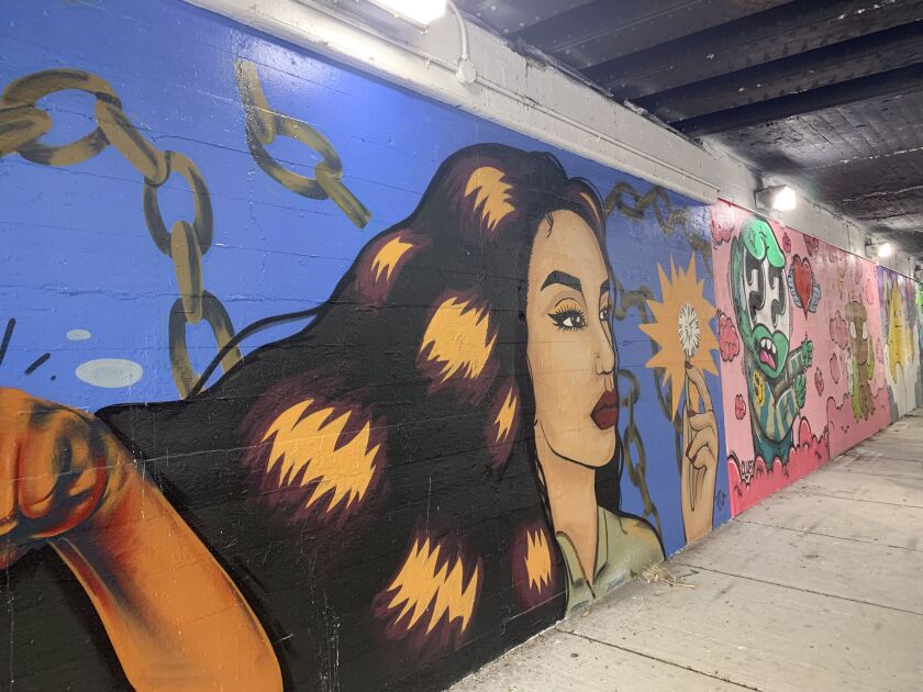 Archer Heights artist Norma Ojeda, who goes by No Art, says that, “as a kid, I always had this inspiration of making a wish by blowing on a dandelion.” So she had her character in the painting do that. “The chains represent struggle — always remember where you came from and focusing on dreams, basically.” Her mural blends into an adjacent painting by Sentrock.