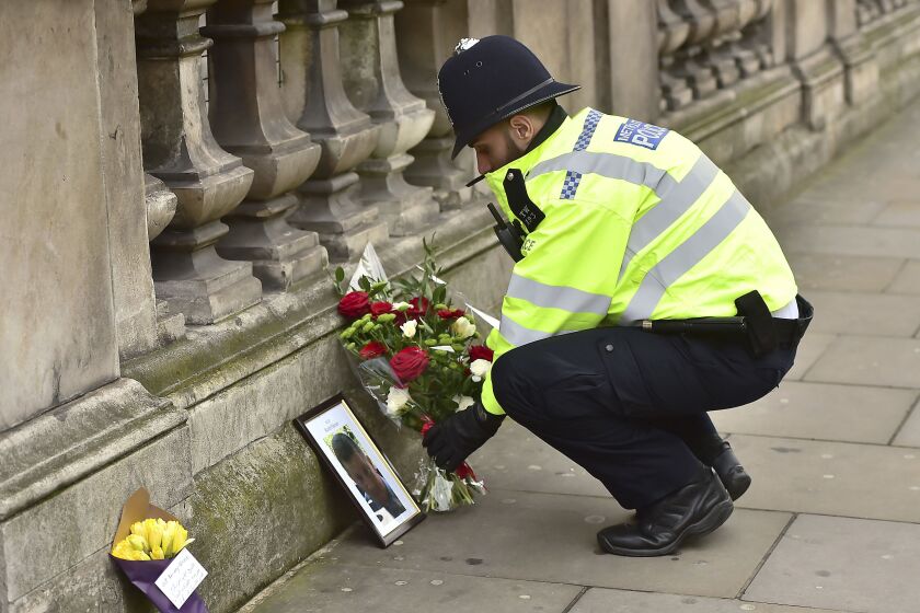 A police officer on Thursday places flowers and a photo of fellow police officer Keith Palmer, who was killed in the attack Wednesday near the Houses of Parliament in London. | Dominic Lipinski/Press Association, distributed by the Associated Press