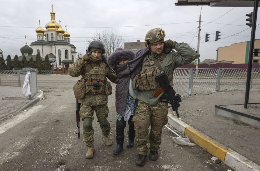 Ukrainian servicemen help an elderly woman, in the town of Irpin, Ukraine, Sunday, March 6, 2022.