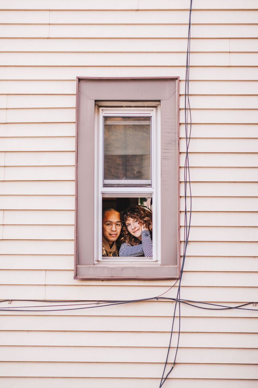 David Yanong Beltran and Diana Bowden peer out their window in Logan Square.