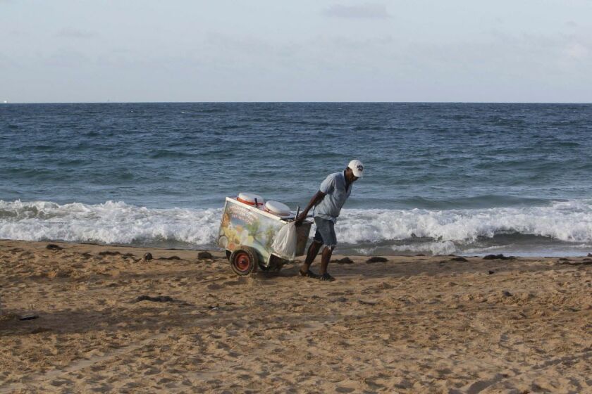 An ice cream vendor pulls a cart at the beach before the anticipated arrival of Hurricane Maria, in San Juan on Sept. 18, 2017. | Ricardo Arduengo/AFP/Getty Images