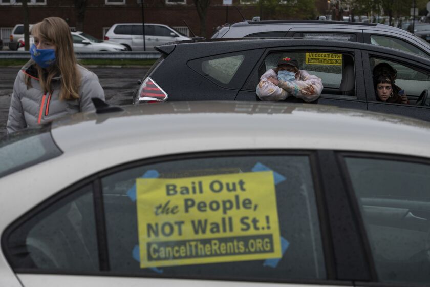 Kathryn Stender (left), Curt Oren, and Jenna Briasco (right), listen to a speech during a protest Saturday in Albany Park that called for a rent freeze amid the coronavirus pandemic.